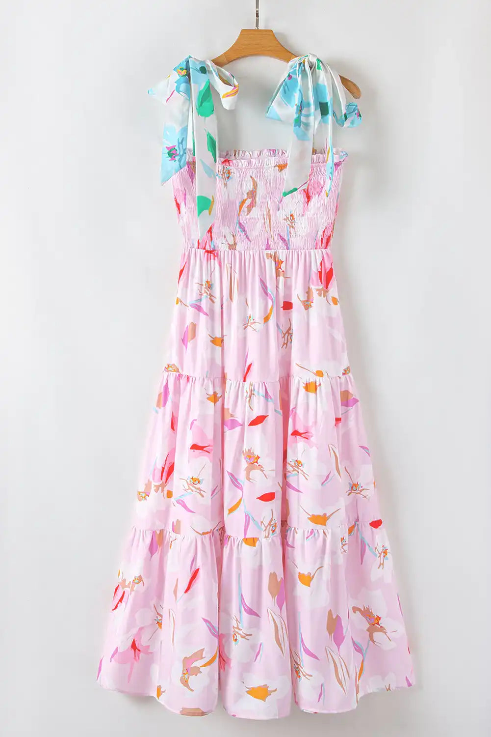 Colorful floral dress on a hanger against a white background
