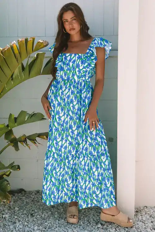Woman wearing a blue and green floral maxi dress with ruffle sleeves, posing outdoors