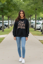 Woman wearing a black sweatshirt with text on a sidewalk with trees and cars in the background