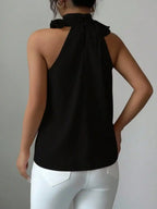 Woman wearing sleeveless black halter top with white jeans, back view, boutique fashion