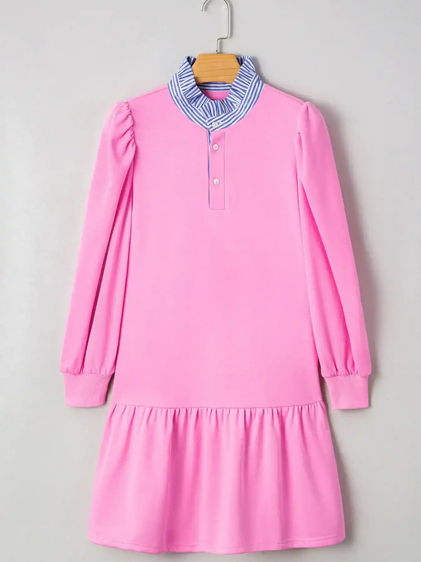 Pink long sleeve dress with ruffled hem and blue striped collar, hanging on a hanger