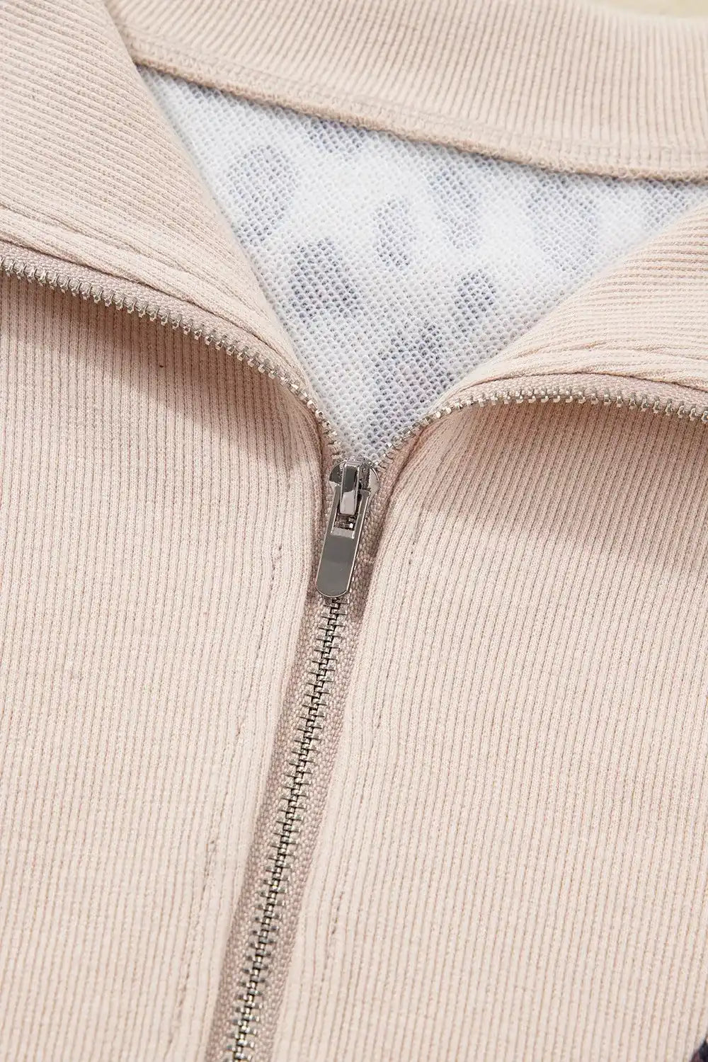 Close-up of beige ribbed zip-up jacket collar and silver zipper