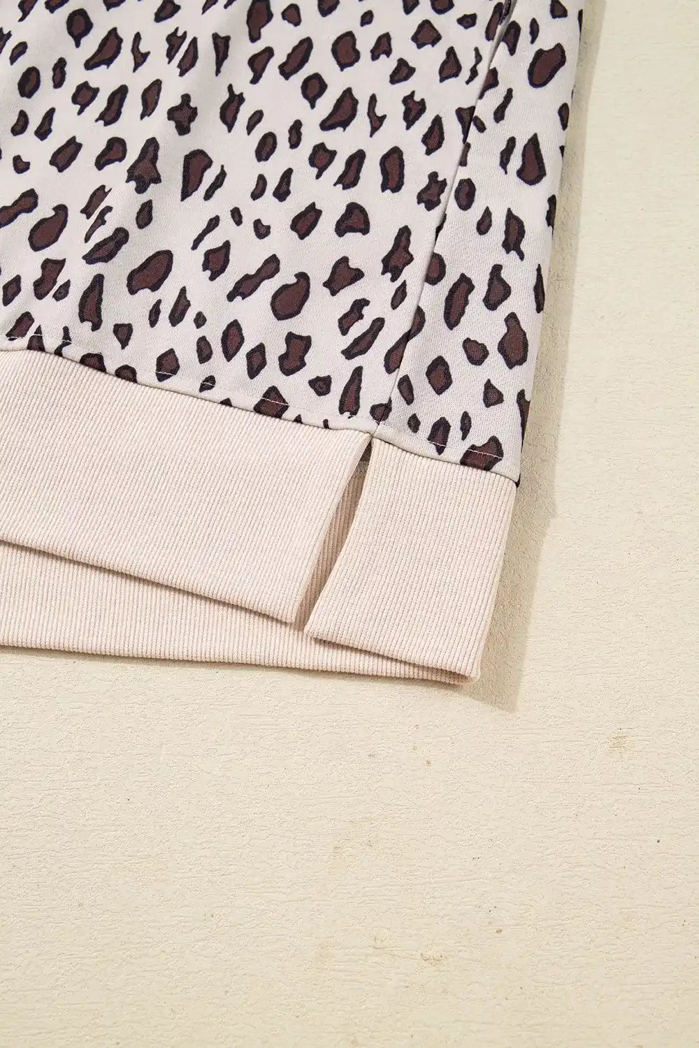 Closeup of beige leopard print sweater hem with ribbed knit trim