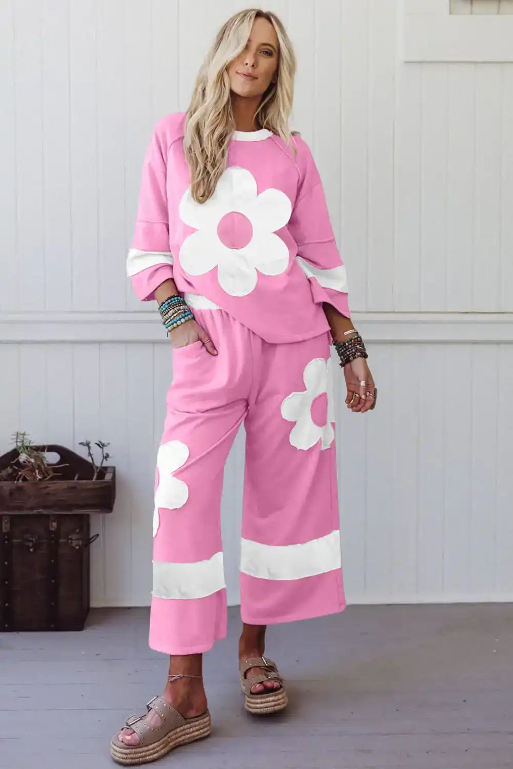 Woman wearing a pink lounge set with large white flower prints and wide-leg pants