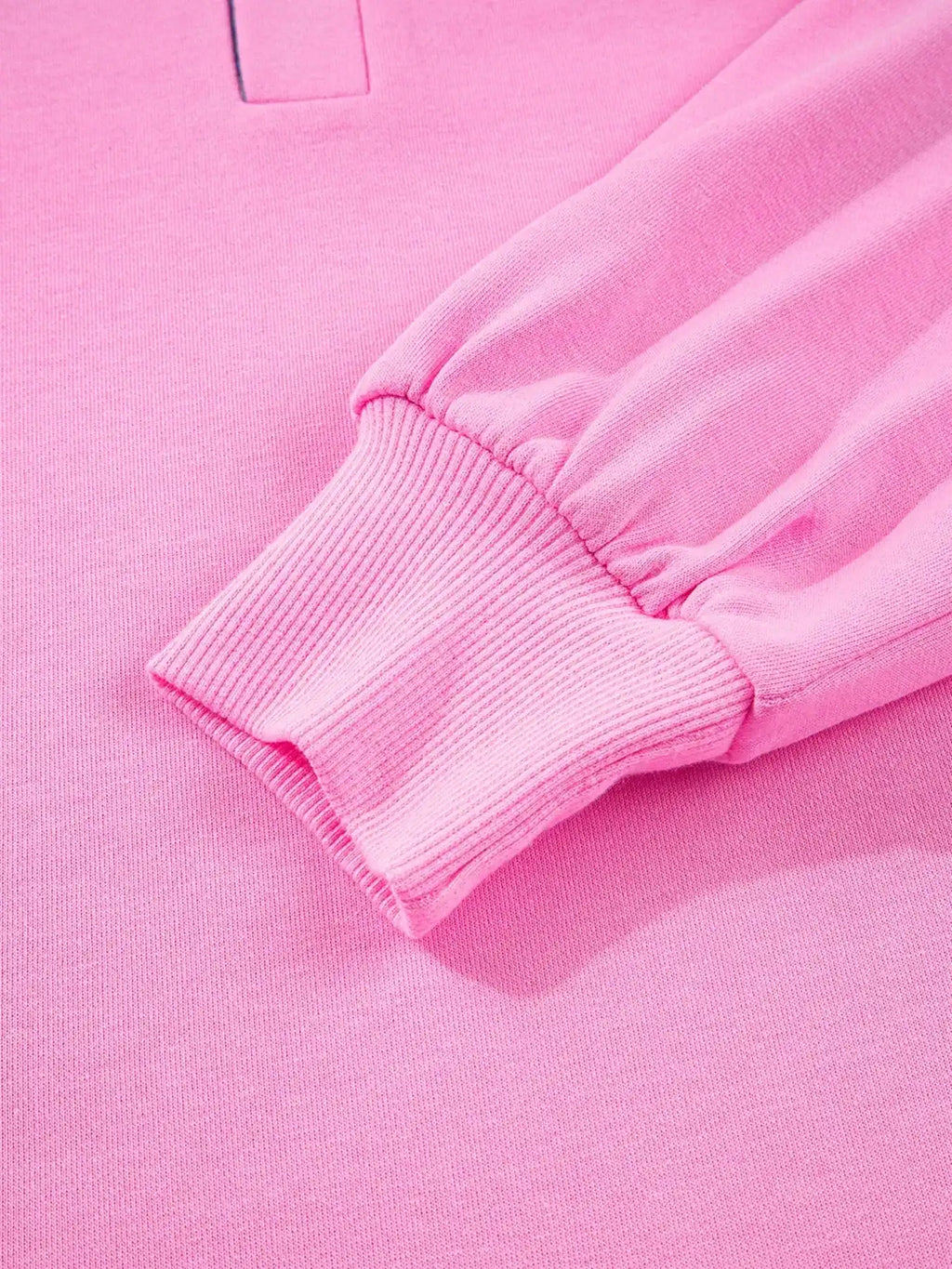 Close-up of pink long-sleeve sweatshirt with ribbed cuff, soft knit fabric