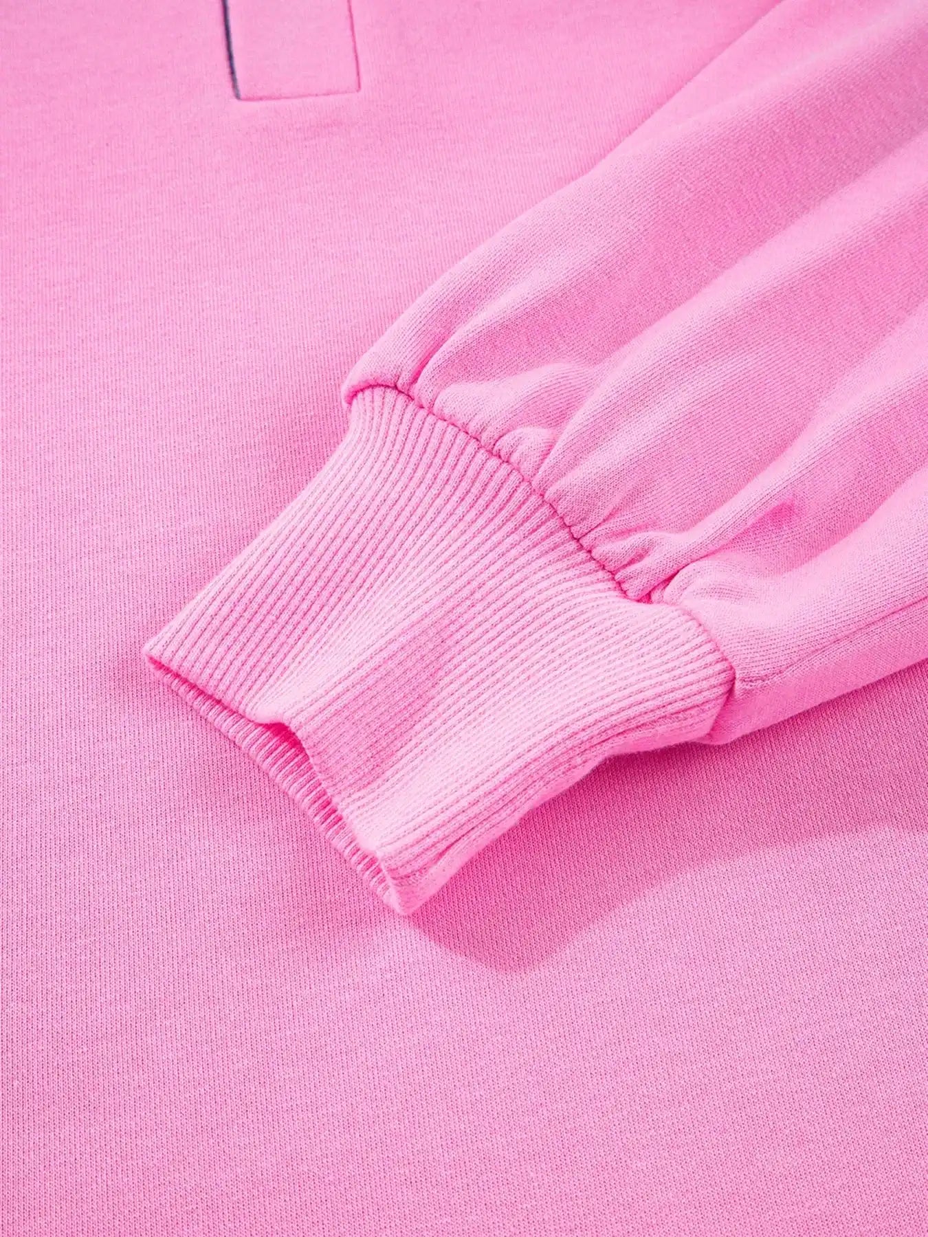 Close-up of pink long-sleeve sweatshirt with ribbed cuff, soft knit fabric