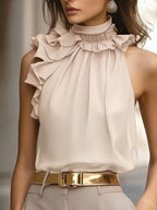 Woman wearing a beige ruffled sleeveless blouse and gold belt, chic boutique fashion style