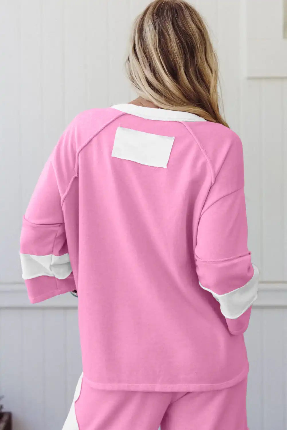 Woman wearing pink lounge set with white color block accents, viewed from the back