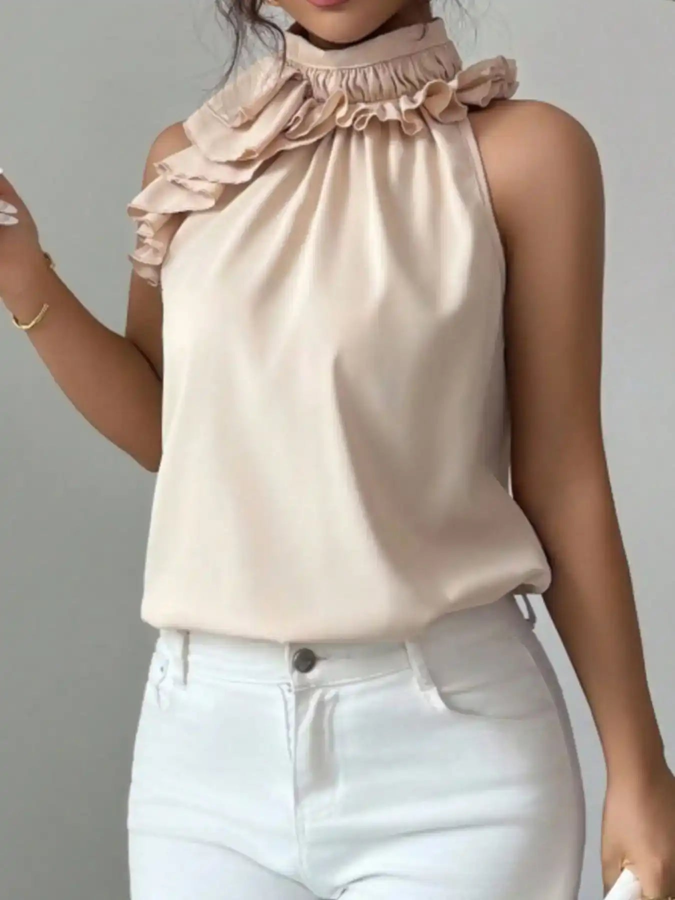 Sleeveless beige ruffle neck blouse paired with high-waisted white jeans, chic women’s outfit