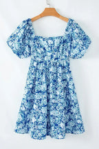 Blue floral puff sleeve summer dress with square neckline hanging on wooden hanger