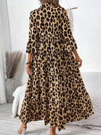Woman wearing a long leopard print maxi dress with ruffled sleeves in a cozy bedroom
