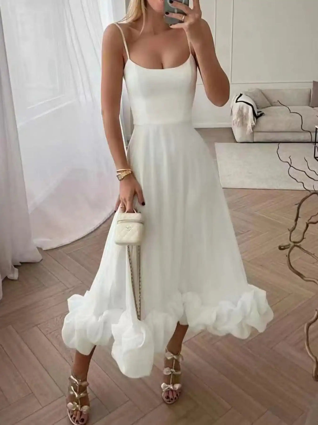 White ruffle hem midi dress with spaghetti straps, paired with gold heels and a mini handbag