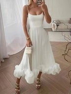 White ruffle hem midi dress with spaghetti straps, paired with gold heels and a mini handbag