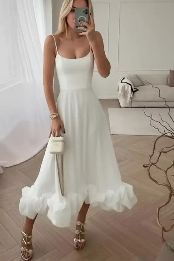 Woman in white ruffle hem midi dress with strappy heels and mini handbag, stylish boutique fashion