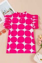 Pink and white polka dot women’s top with ruffled sleeves on beige background