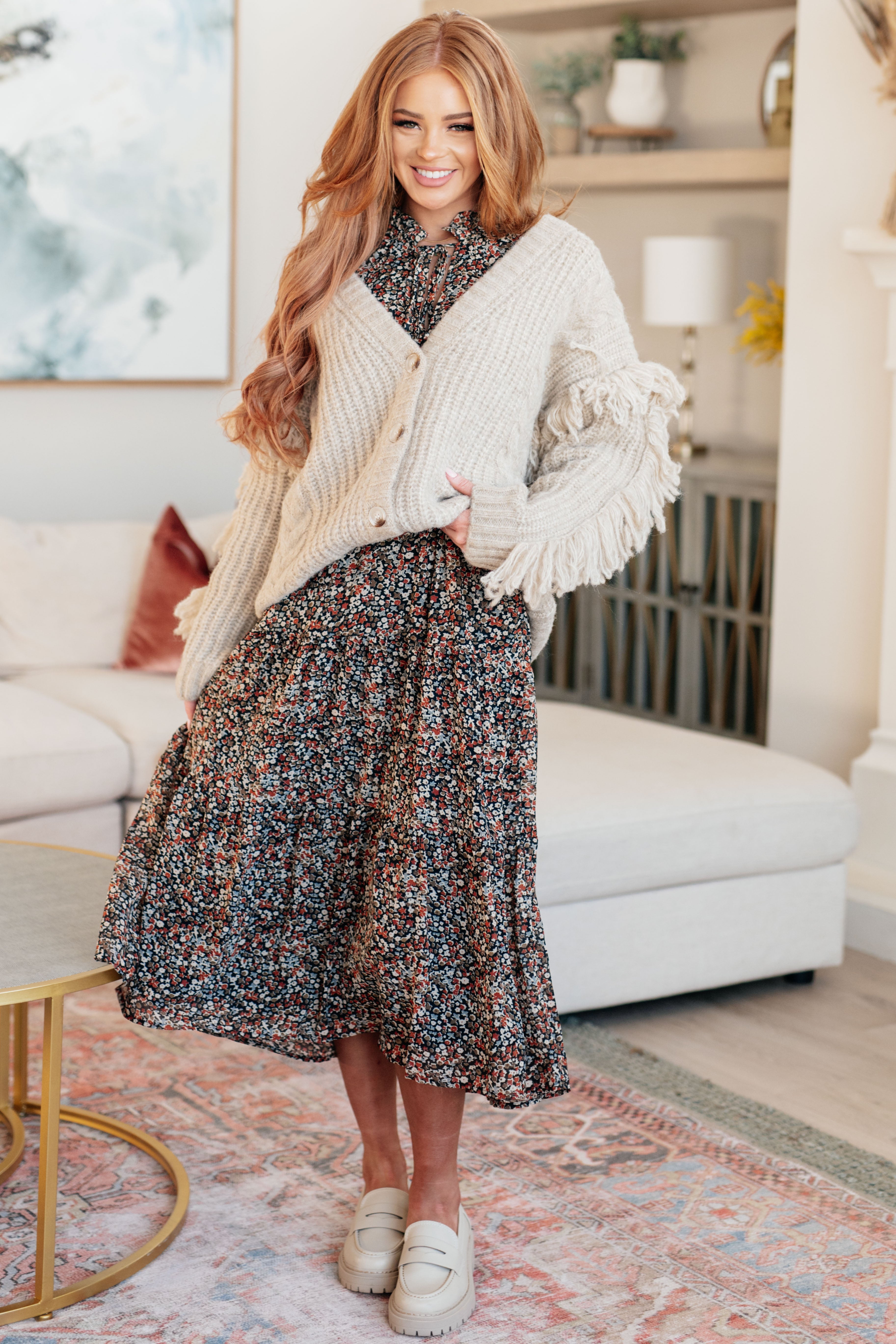 Woman in a floral dress and white cardigan in a living room setting