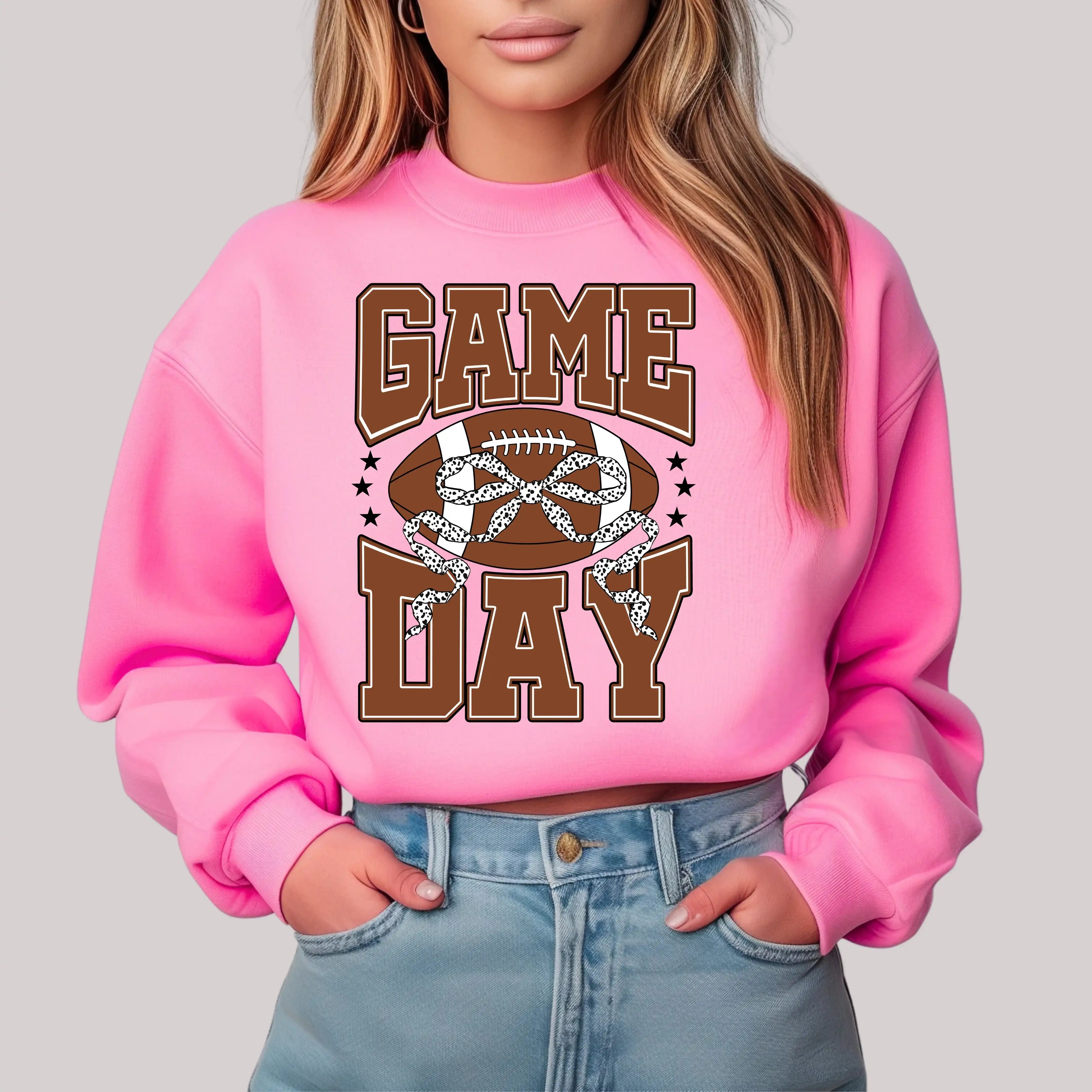Person wearing a pink sweatshirt with 'Game Day' and football graphic on a plain background