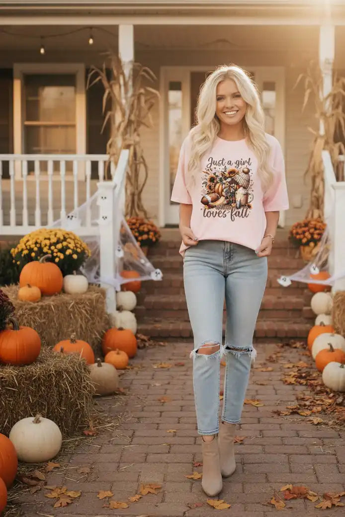 Woman standing on a porch decorated for fall with pumpkins and hay bales.