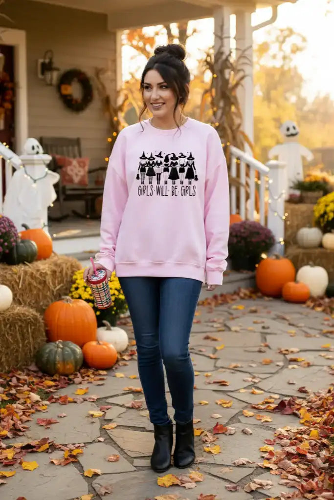 Woman in a pink sweatshirt standing in front of a decorated house for Halloween.