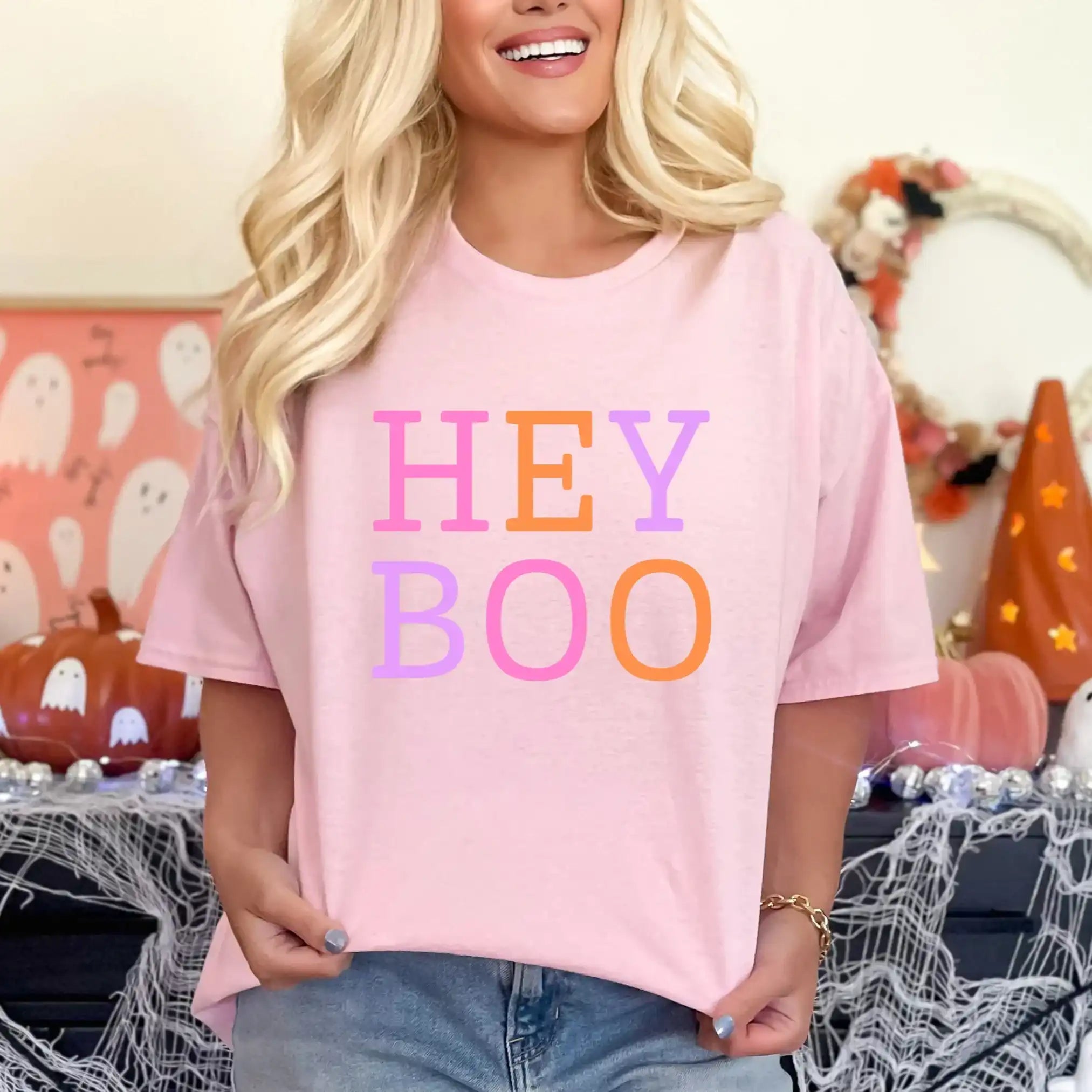 Person wearing a pink 'HEY BOO' t-shirt in a Halloween-themed setting