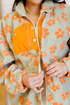 Person wearing a floral coat with orange flowers on a light green background