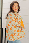 Woman wearing a floral patterned top with orange flowers on a light background