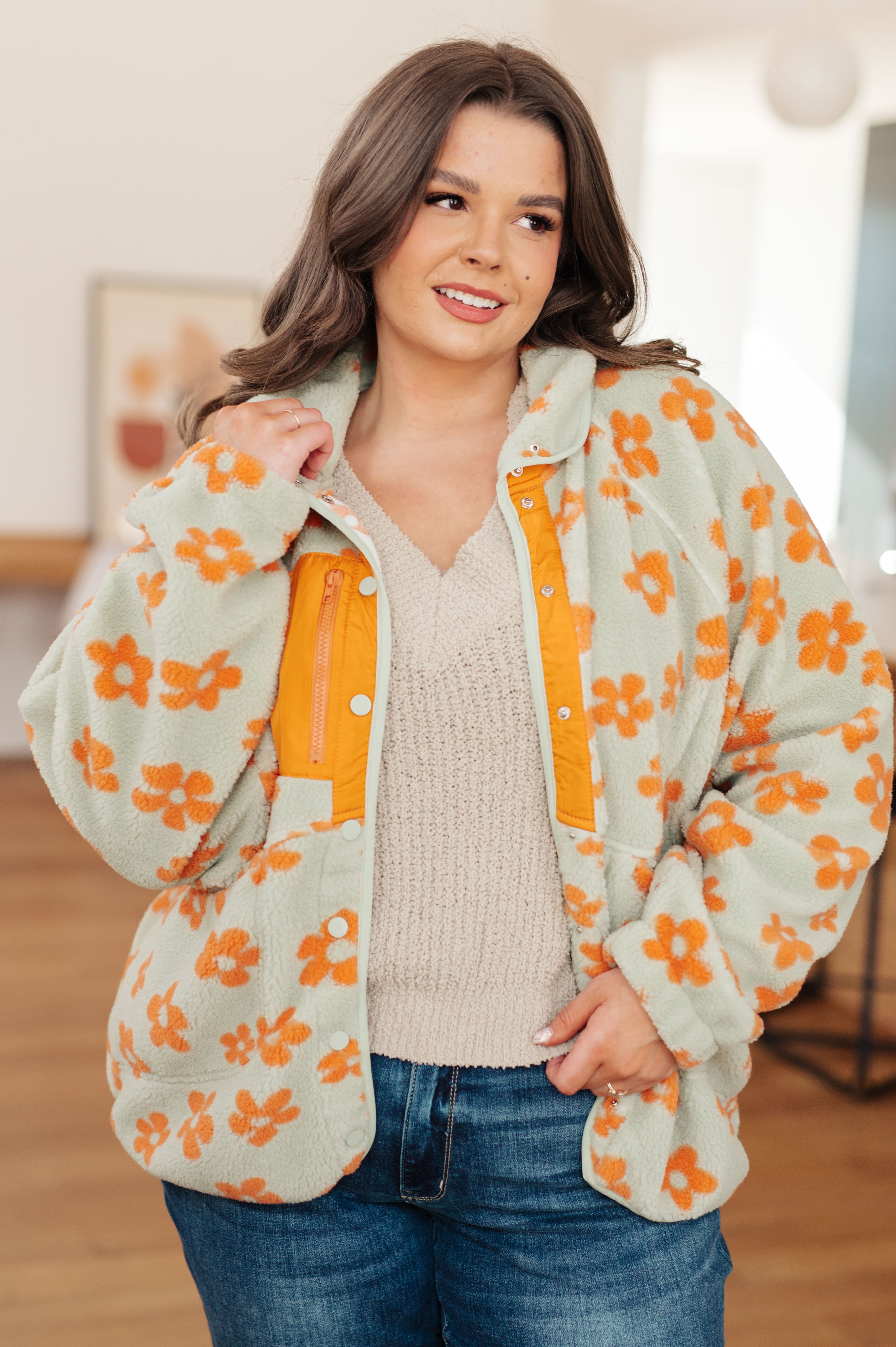 Woman wearing a floral patterned jacket with orange flowers indoors.