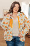 Woman wearing a floral patterned jacket with orange flowers indoors.