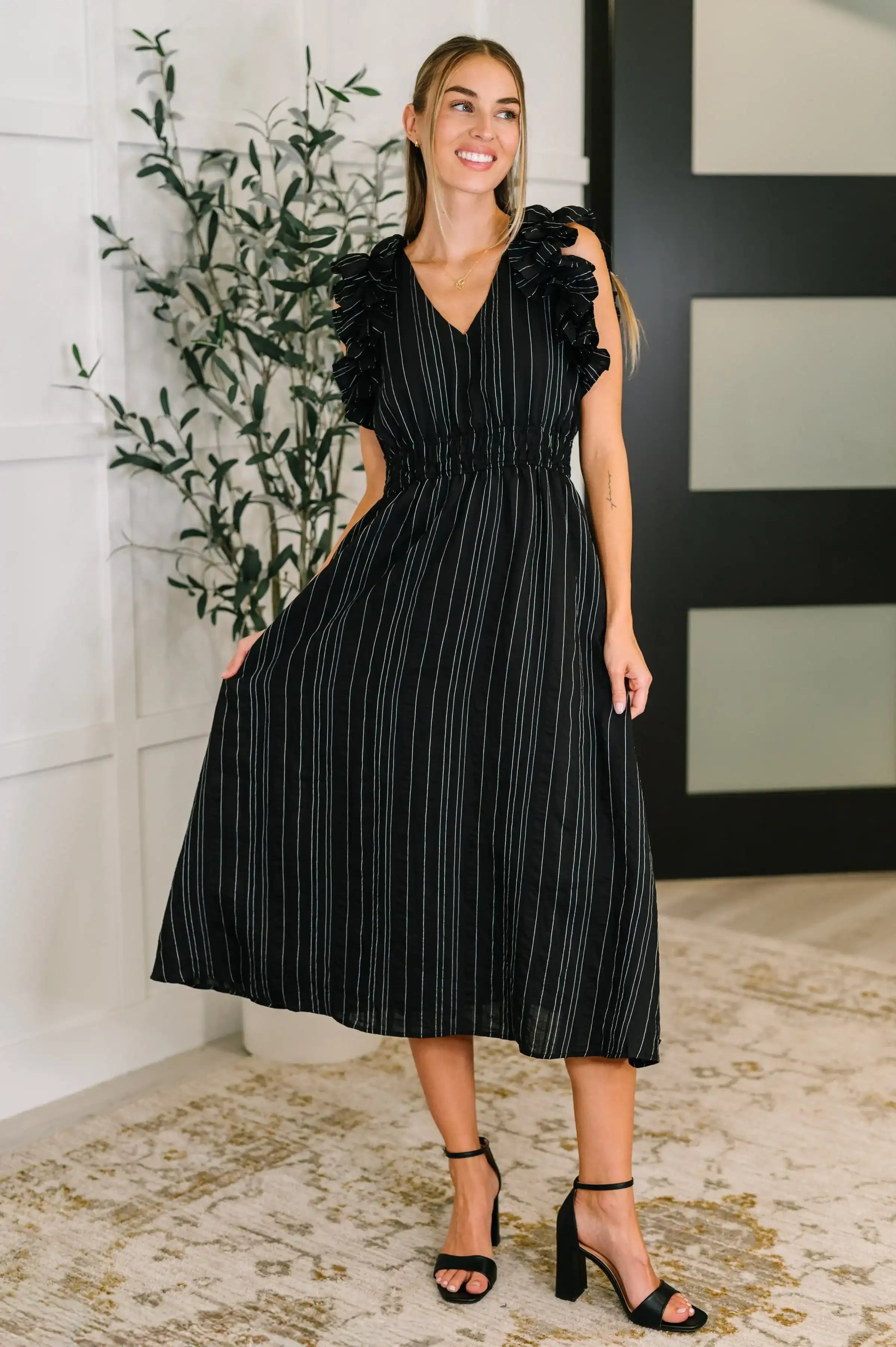 Woman wearing a black dress with white stripes indoors.