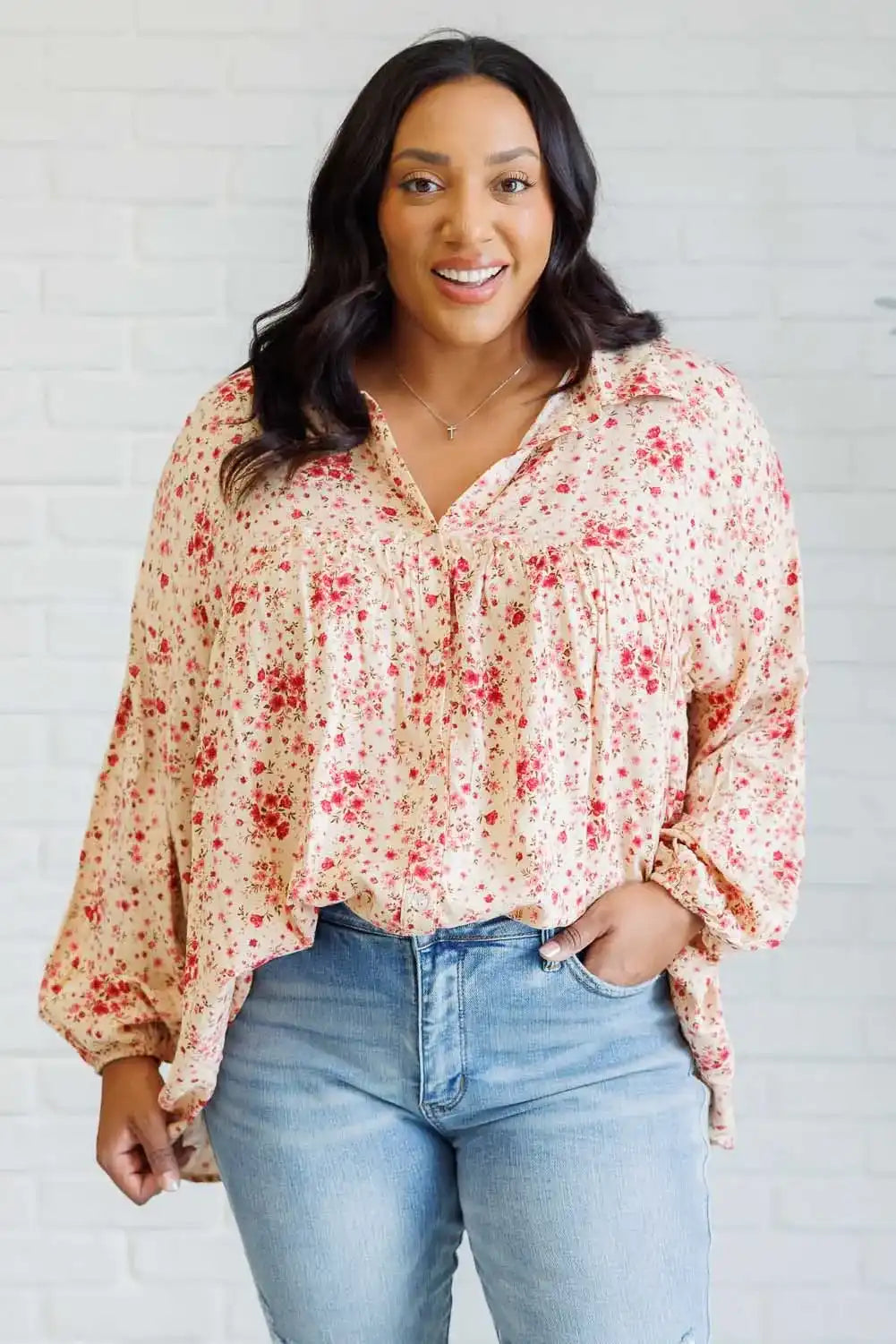 Woman wearing a floral blouse and jeans against a white background