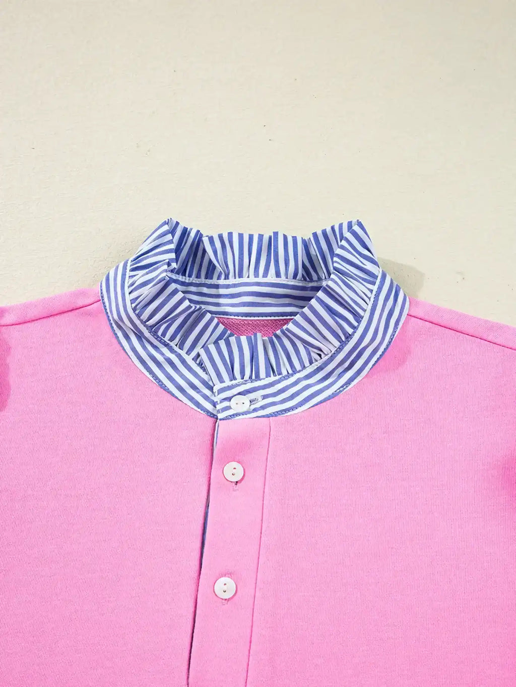 Pink women's blouse with blue and white striped ruffle collar and white buttons