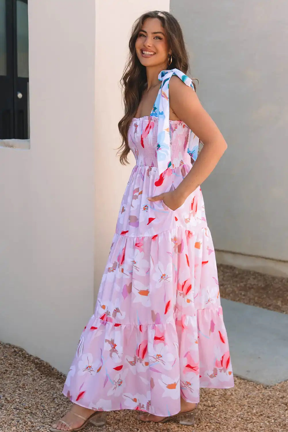 Woman wearing a floral dress standing against a white wall.