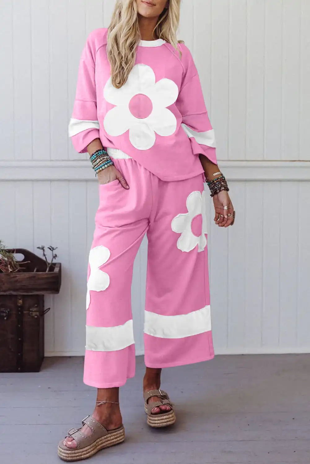 Woman wearing pink loungewear set with large white flower print and sandals