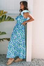 Woman wearing a blue floral maxi dress with ruffle sleeves, standing outdoors