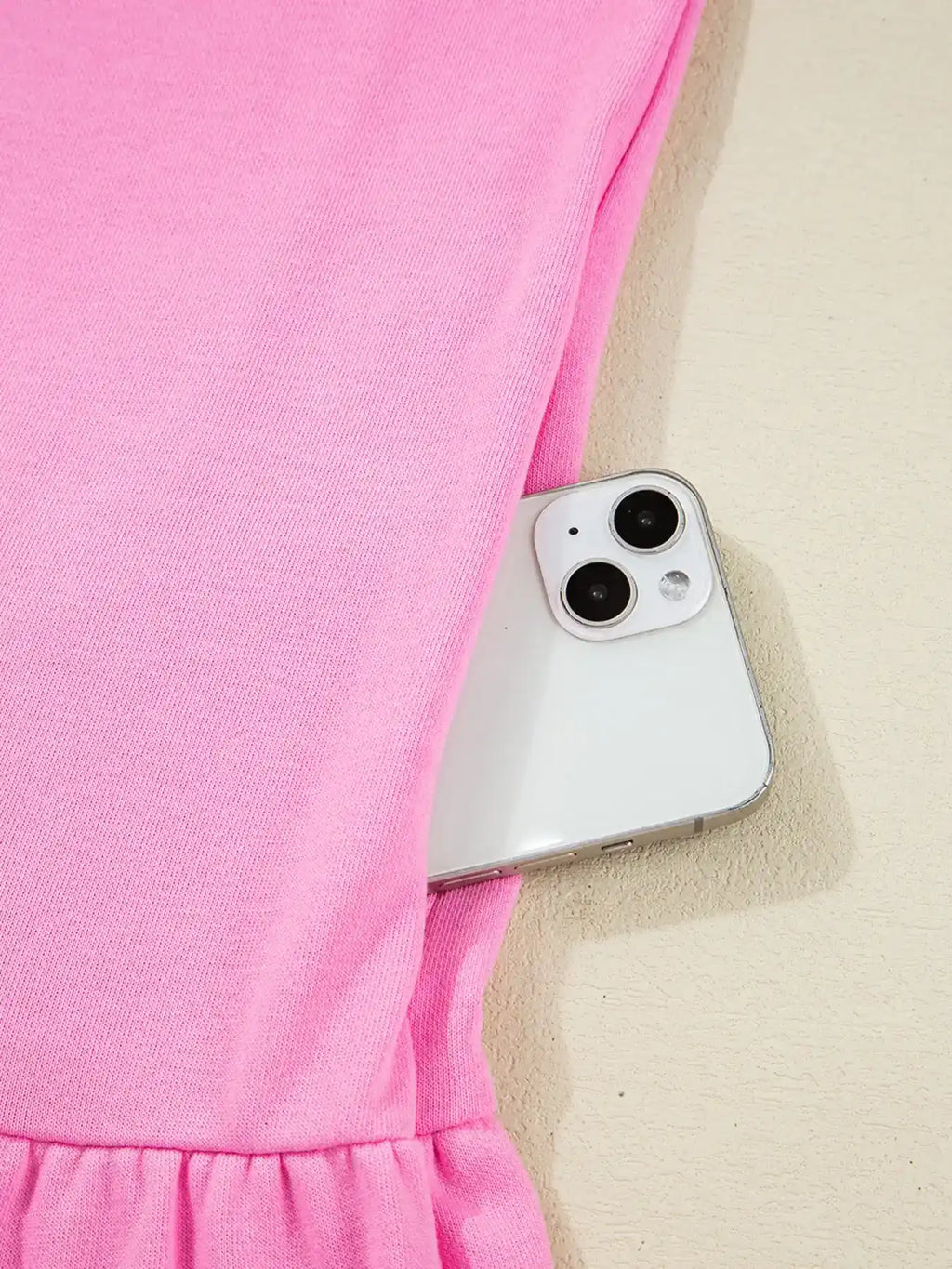 Pink dress with elastic waist, side pocket holding a smartphone, close-up view