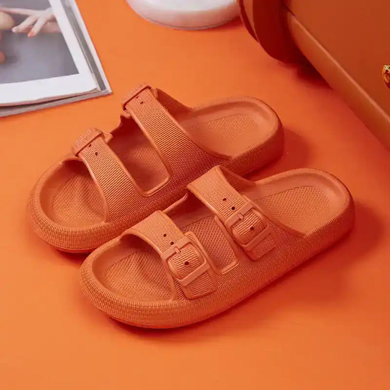 Orange double-strap women’s slide sandals with buckles on matching orange background