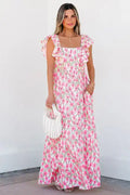 Woman in a pink floral maxi dress with ruffle sleeves holding a white handbag