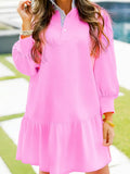 Woman wearing a loose pink long sleeve dress with ruffle hem, outdoor setting