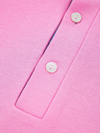 Close-up of pink knit women's polo shirt with white buttons