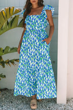 Woman wearing a blue floral print maxi dress with ruffle sleeves, standing outdoors