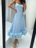Light blue ruffle hem midi dress with spaghetti straps, paired with embellished heels and a beaded bag.
