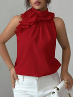 Woman wearing a sleeveless red ruffle blouse with high neck and white jeans