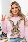 Woman wearing a pink bunny graphic sweatshirt and denim shorts, making a peace sign