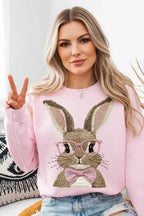 Woman wearing a pink bunny graphic sweatshirt and denim shorts, making a peace sign