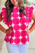 Woman wearing a pink and white polka dot ruffle sleeve blouse and light blue pants