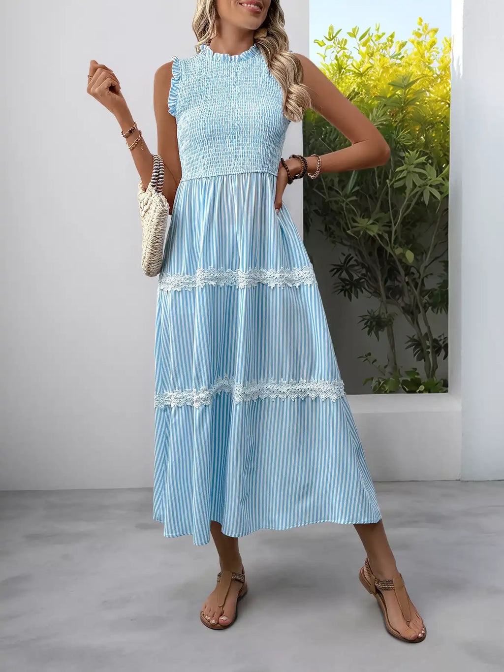 Light blue striped tiered midi dress with lace trim, sleeveless high neck, paired with sandals and woven bag