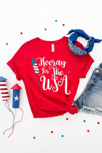 Red t-shirt with 'Hooray for the USA' text, denim shorts, and small American flag items on a white background.